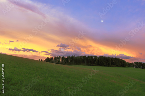 Magic evening sky, colourful sunset clouds with moon, dusk landscape of Jura Mountains, Switzerland.