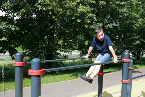 Boy trains abdominal muscles on uneven bars