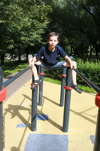 Child trains abdominal muscles on uneven bars