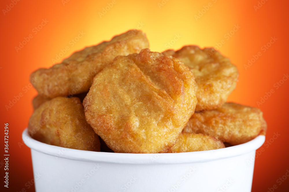 Bucket with delicious chicken nuggets on orange background, closeup Bucket with delicious chicken nuggets on orange background, closeup