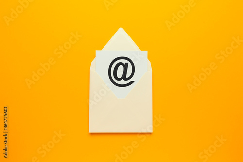 Envelope with e-mail symbol on yellow background, concept of corporate communication and marketing mailings.
