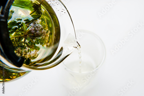 Close up of  green tea being poured from teapot into transparent glass