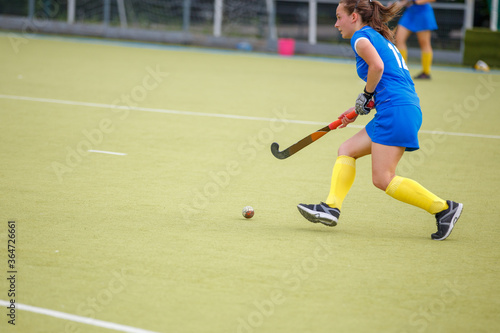 Young woman playing field hockey game on the pitch