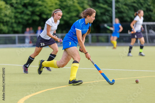 Young women playing field hockey game on the pitch