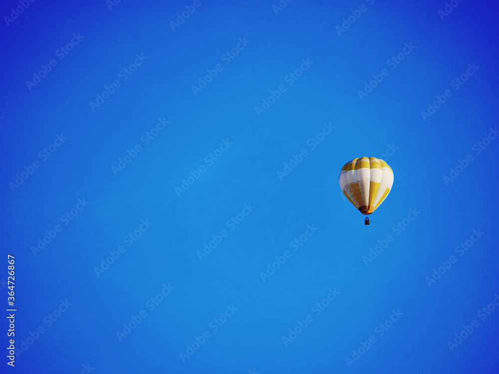 Fototapeta premium balloon flying mid-air in sunshine against blue sky