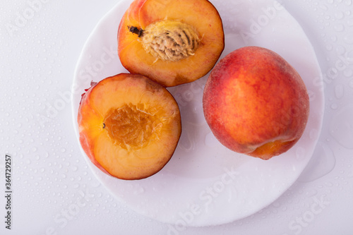 Nectarine peaches with a slice and leaves on a white background