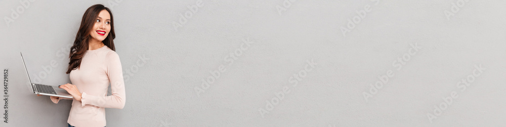 Fototapeta premium Half-turn image of cute female in casual clothes working on notebook