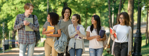 Multiethnic group of young cheerful students walking