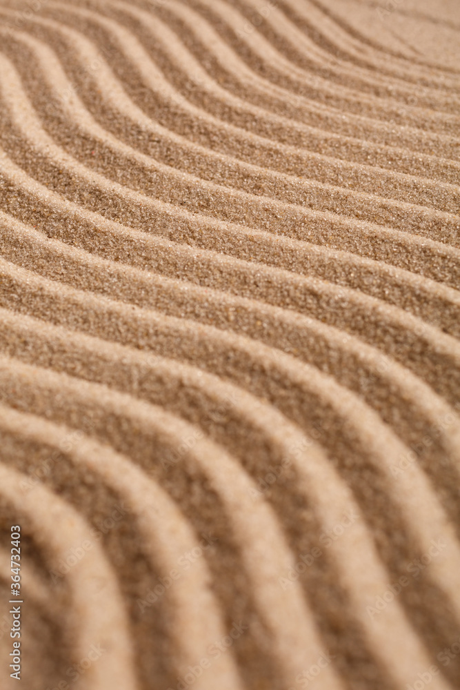 Wavy pattern on a beach in the summer. The textured surface of sand on the beach after a strong wind in the form of waves close up. Wavy pattern on a beach in the summer. The textured surface of sand on the beach after a strong wind in the form of waves close up.