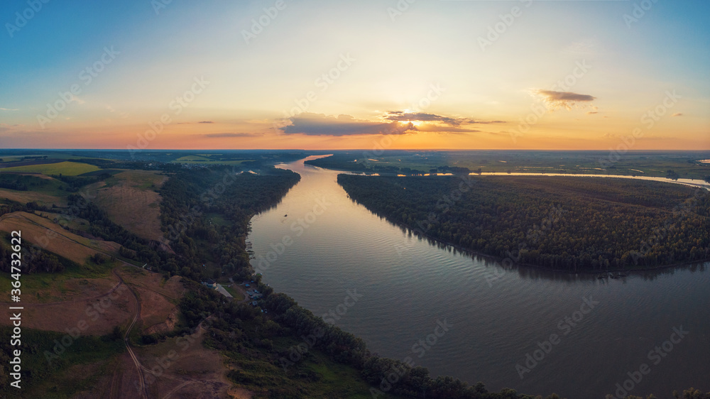 Aerial drone view of river landscape in sunny summer evening. Top view of siberian Ob river from high attitude in summer sunset. Panorama, bird's eye view
