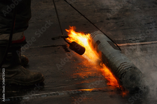 Laying of roofing felt from the roll with a flame from the burner close-up.