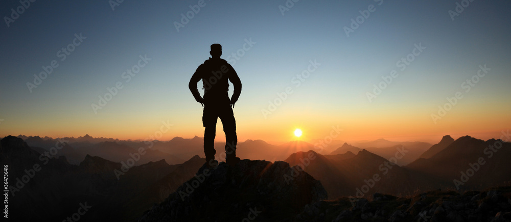 Εκτύπωση καμβά Man Silhouette reaching summit enjoying freedom and looking towards mountains sunset