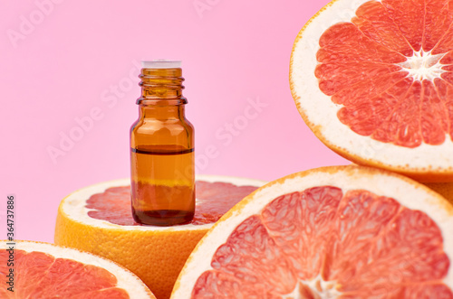 Photos Bottle with essential citrus oil and fresh red grapefruits.