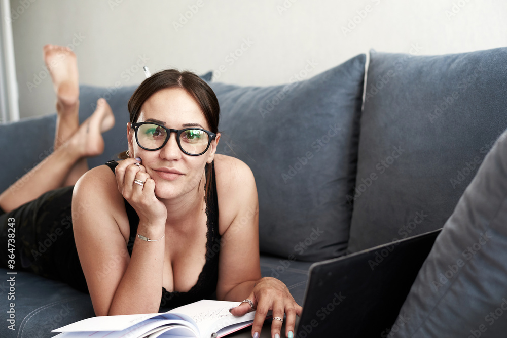 A woman is laying on the sofa. A woman is surfing the computer and working. A woman work at home