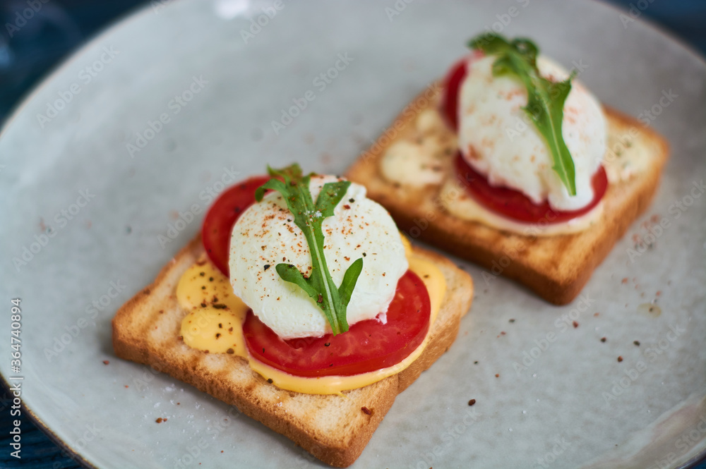 Tasty home breakfast of square toast with sliced fresh tomato and egg benedict with urugula. Tasty home breakfast of square toast with sliced fresh tomato and egg benedict with urugula.