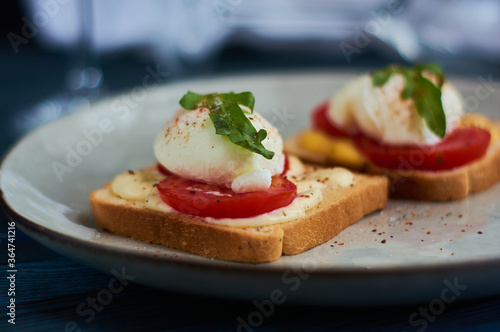 Tasty home breakfast of square toast with sliced fresh tomato and egg benedict with urugula.