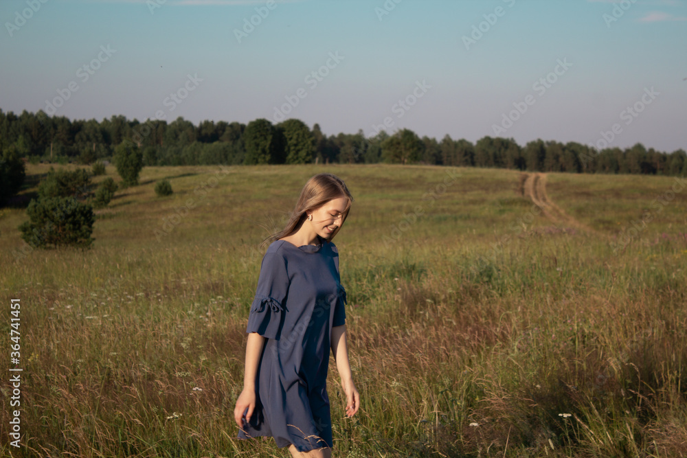 Beautyful woman walking outdoors. Fashion elegant lady in blue dress on nature