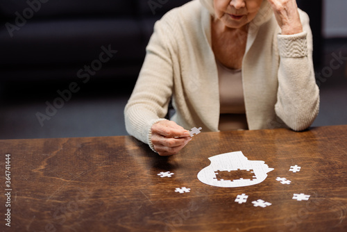Фотография senior woman collecting jigsaw puzzle as dementia therapy