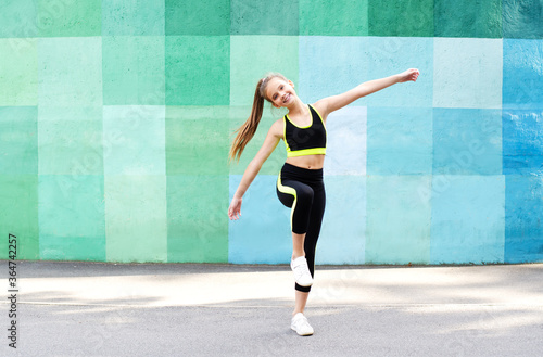 Fitness sport young girl in sportswear doing yoga fitness exercise on a wall background. Sporty gymnast child preteen training outdoor.