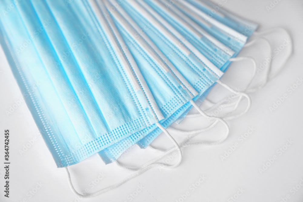Blue medical masks lie on a white table - face mask against bacteria and viruses, top view Blue medical masks lie on a white table - face mask against bacteria and viruses, top view