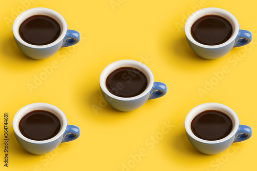 Minimal pattern with cup of black coffee at yellow background