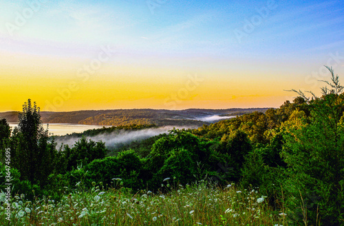 Sunset over Norfork Lake with fog rolling in over the mountains 