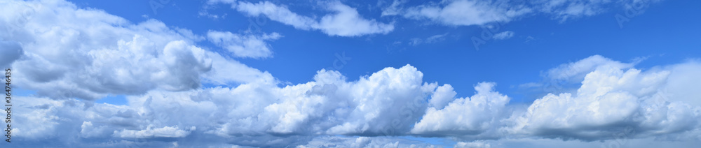 Obraz premium July is the summer sky. Panoramic photo of dense, brightly white clouds flying low above the ground.