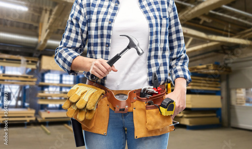 industry, production and job concept - close up of woman or worker with hammer and working tools on belt over factory workshop on background © Syda Productions