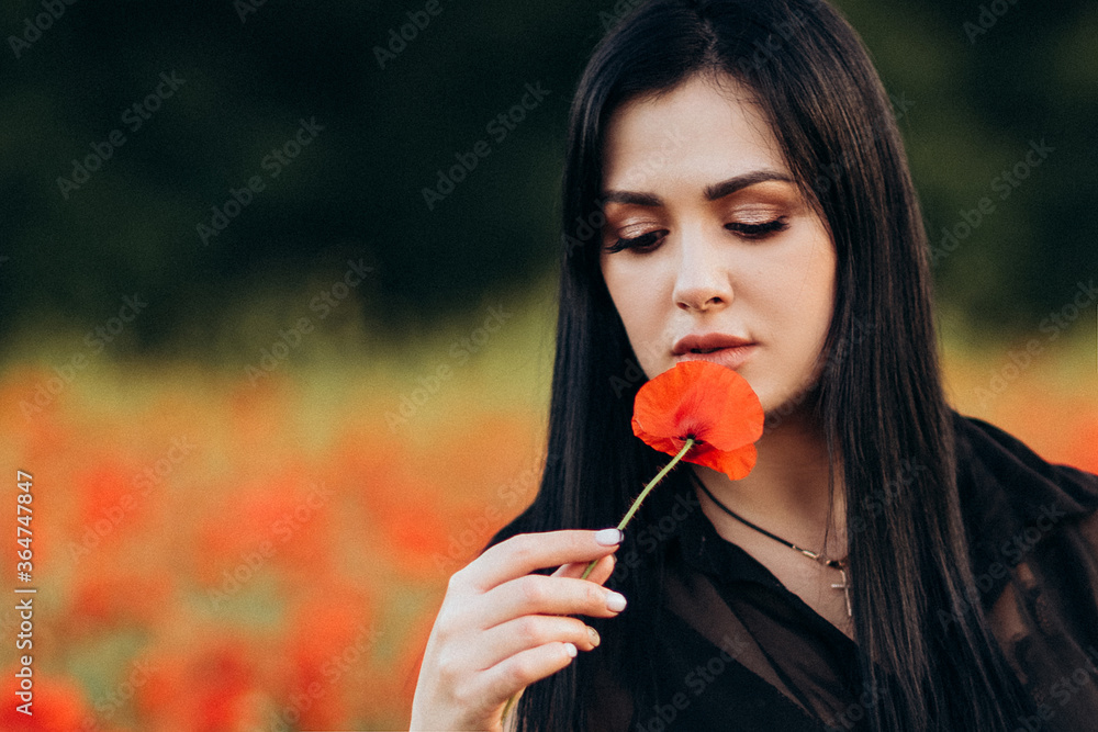 Beautiful long hair woman in a black dress in a poppy field Beautiful long hair woman in a black dress in a poppy field