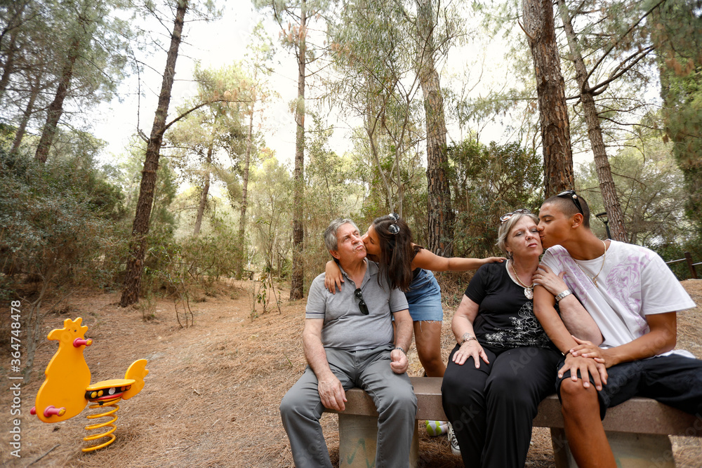 Nipoti mulatti Italo-Brasiliano , baciano i nonni di origine europea seduti nella panchina in un parco