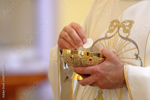 Fototapeta Holy host in the hands of the priest on the altar during the celebration of the