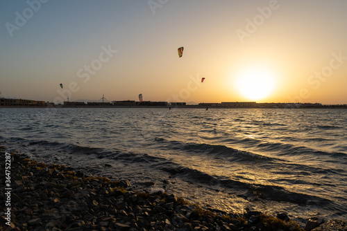 Kiters gliding over the Red sea surface. Extreme outdoor sport/activity/recreation. People in sport equipment riding on the water surface. Stunning marine scene. Beautiful sunset background.