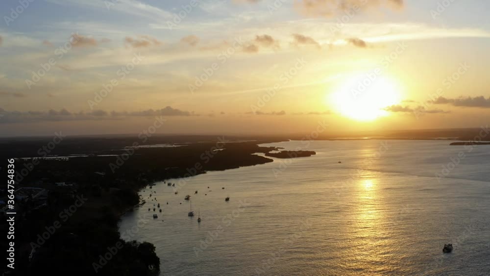 Stunning aerial drone descending shot of a golden sunset reflecting onto a giant amazonian river in the tropical beach town of Tibau do Sol near Pipa in Northern Brazil on a warm summer evening. Stunning aerial drone descending shot of a golden sunset reflecting onto a giant amazonian river in the tropical beach town of Tibau do Sol near Pipa in Northern Brazil on a warm summer evening.