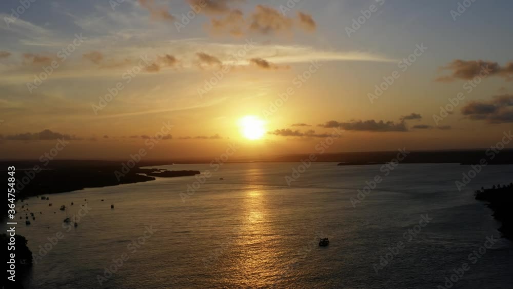 Stunning aerial drone static shot of a golden sunset reflecting onto a giant amazonian river in the tropical beach town of Tibau do Sol near Pipa in Northern Brazil on a warm summer evening. Stunning aerial drone static shot of a golden sunset reflecting onto a giant amazonian river in the tropical beach town of Tibau do Sol near Pipa in Northern Brazil on a warm summer evening.