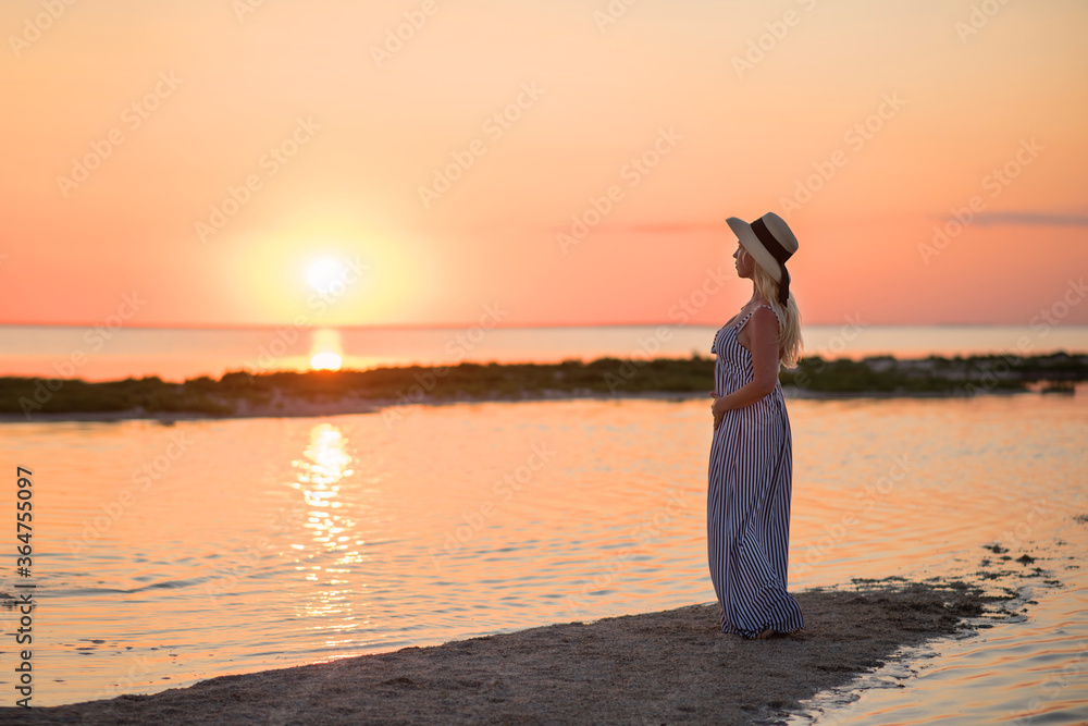 Fototapeta premium woman on the beach. woman on the beach at sunset. young woman in white dress on the beach