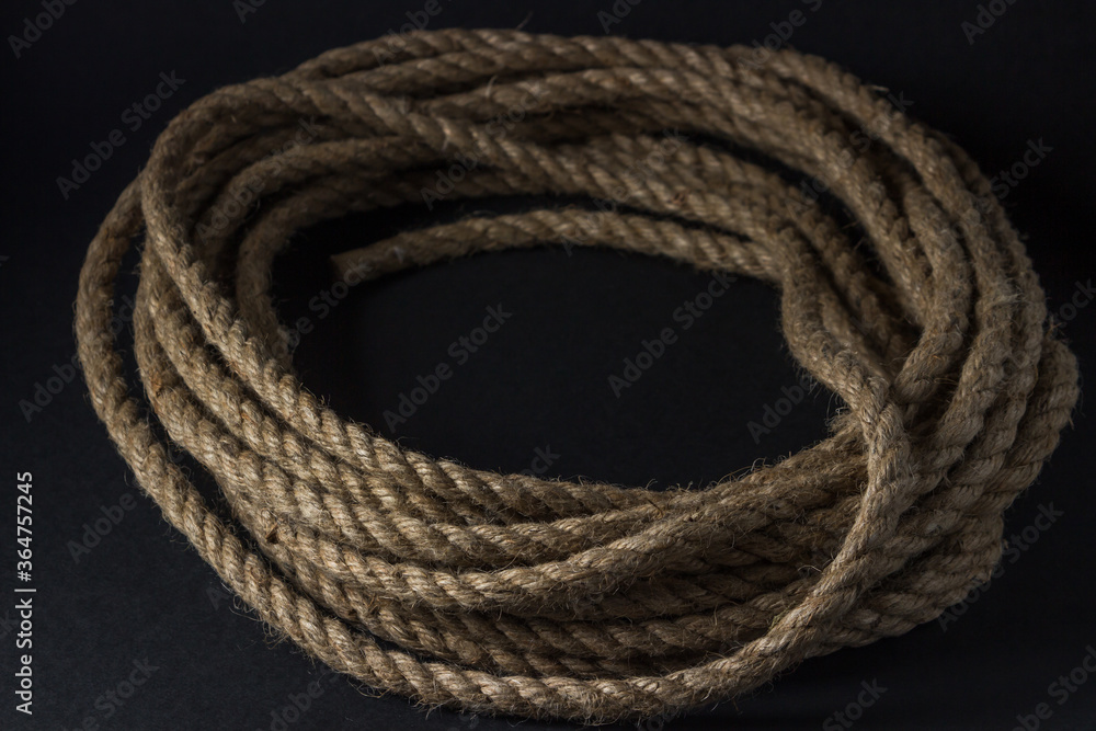 Jute rope lies on a black background. Rope rolled up in a circle Jute rope lies on a black background. Rope rolled up in a circle