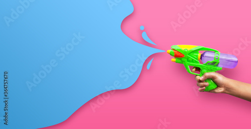 Obraz na plátně Hand holding plastic water gun on pink background