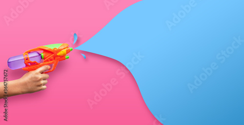 Hand holding plastic water gun on pink background photo