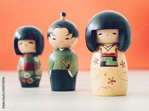 Photo Closeup shot of three different Japanese dolls with an orange background