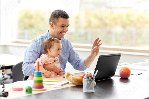 remote job, multi-tasking and family concept - middle-aged father with baby working on laptop at home office