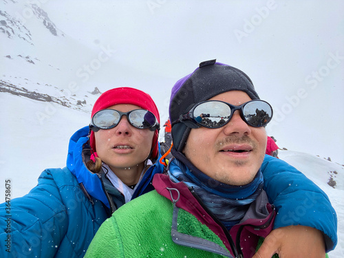 Two climbers - a guy and a girl - take a selfie at the snowy slope of the northern Elbrus region.