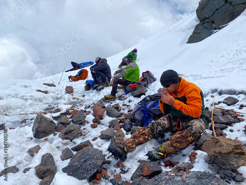 Climbers rest on the rocks on the slopes of Elbrus. Snowy slopes of the northern Elbrus region.