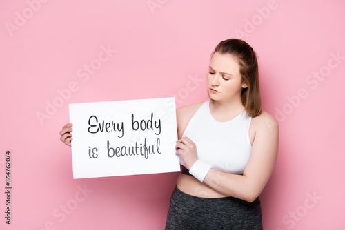 Foto serious overweight holding placard with every body is beautiful inscription on p