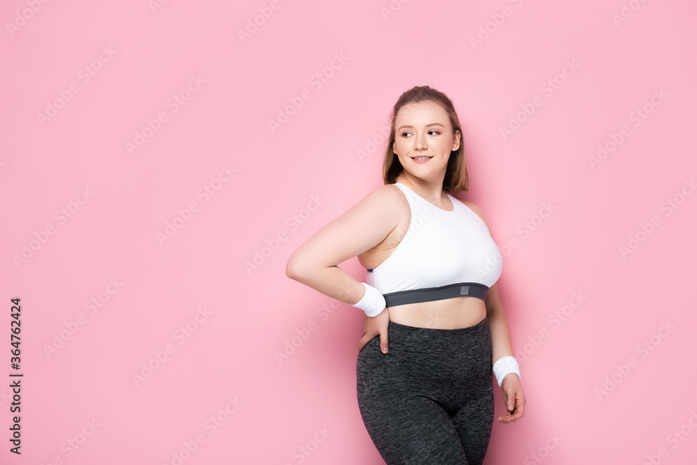 pretty, smiling overweight girl standing with hand on hip on pink pretty, smiling overweight girl standing with hand on hip on pink
