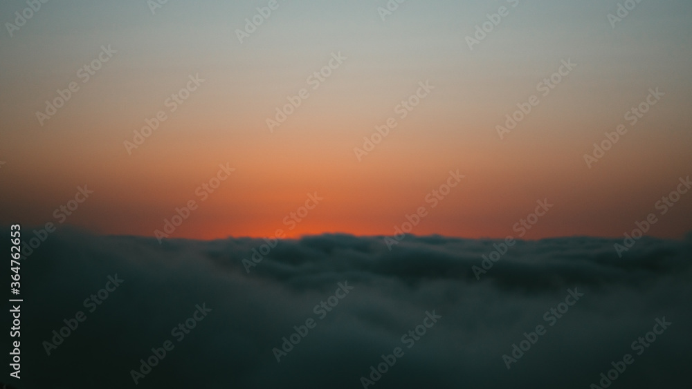 sunset over the clouds on a cliff