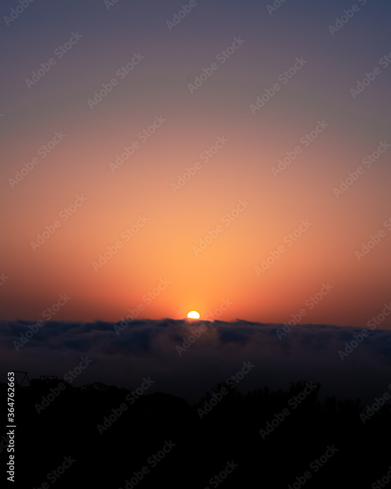 Fototapeta premium sunset over the clouds on a cliff