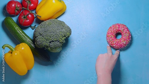 Female hand goes like a little man chooses between healthy food and junk food and decides to take fresh broccoli