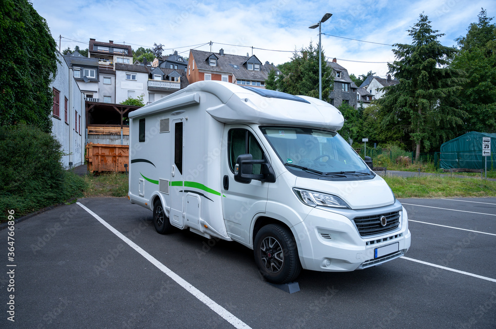 modern motorhome stands on a pitch made of concrete underground in front of a half-timbered town modern motorhome stands on a pitch made of concrete underground in front of a half-timbered town