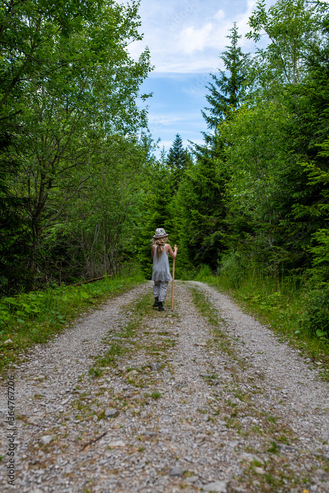 Fototapeta premium Kleiner blonder Junge. Wandert den Berg auf einem schotterweg hinauf
