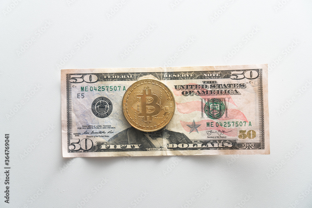 Biktcoin coin lies on paper dollar banknotes. Concept of virtual currency in exchange Biktcoin coin lies on paper dollar banknotes. Concept of virtual currency in exchange